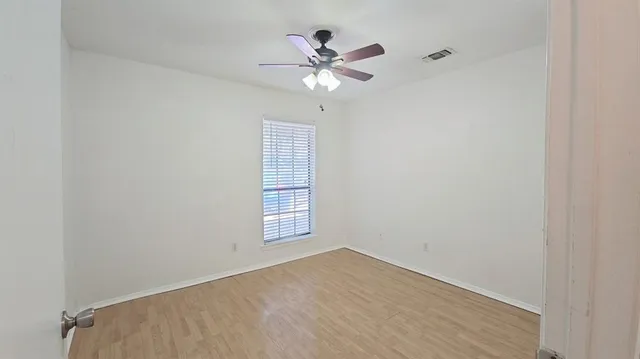 an empty room with a window and a ceiling fan