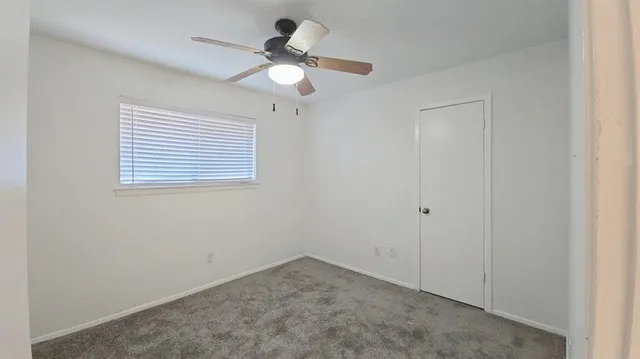 an empty room with a window and a fan