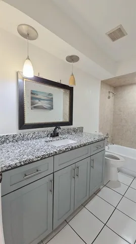 a bathroom with a granite countertop sink a toilet and bathtub