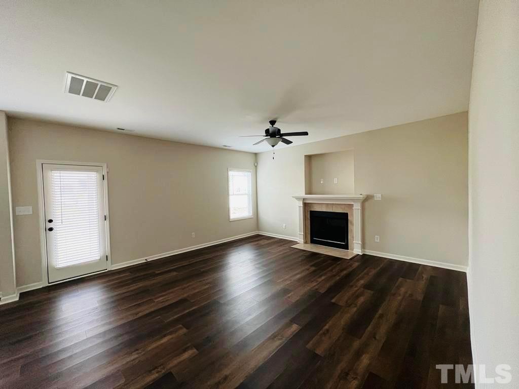 111 Tang Circle Garner, NC 27529 - Photo 12 of 16 an empty room with wooden floor a fireplace and windows