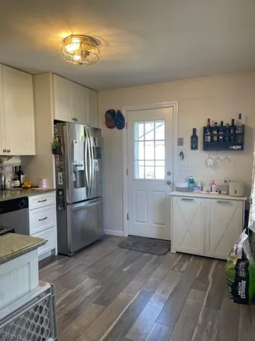 a kitchen with a sink dishwasher a refrigerator and a stove with wooden floor