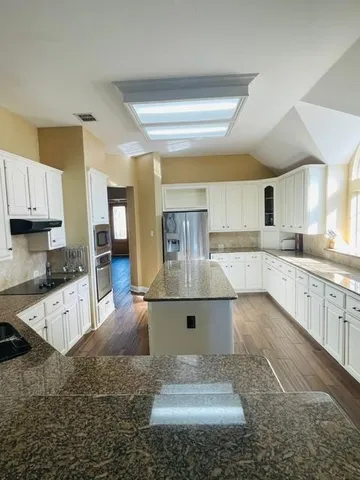 a large kitchen with kitchen island sink stainless steel appliances and cabinets