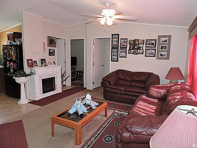 915 North 5000 W Road Hinckley, UT 84635 - Photo 2 of 27 Living area featuring a decorative fireplace with a white mantel, ceiling fan with light fixture, and neutral wall tones
