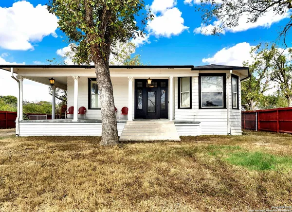 a view of a house with backyard and a tree