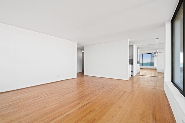 5455 North Sheridan Road, Unit 2301 Chicago, IL 60640 - Photo 5 of 18 an empty room with wooden floor and windows