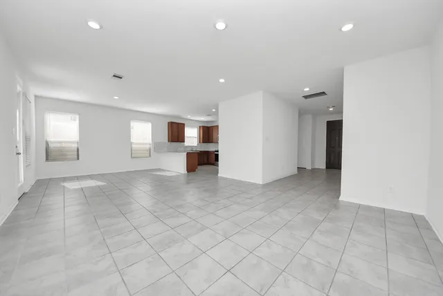 an empty room with kitchen and windows