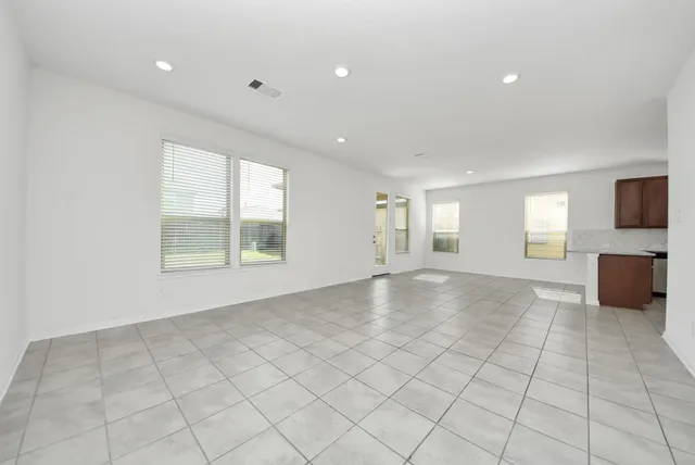 an empty room with windows and fireplace