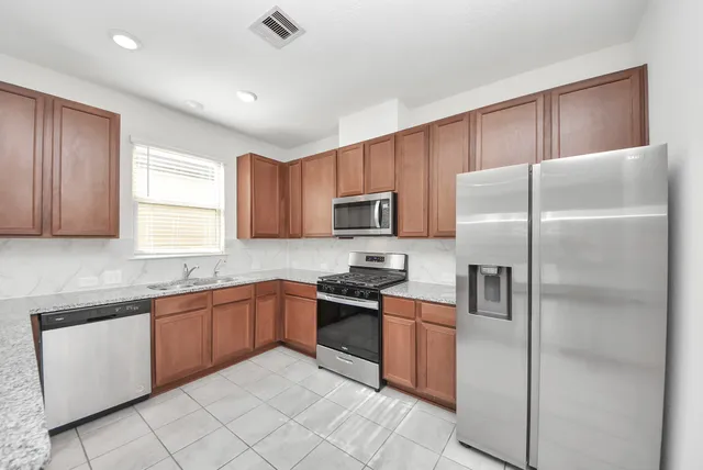 a kitchen with stainless steel appliances granite countertop a stove a sink and a microwave