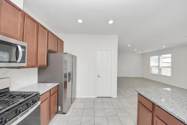 a kitchen with granite countertop stainless steel appliances a refrigerator sink and microwave