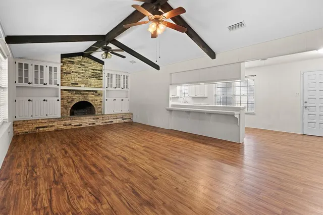 a view of a livingroom with wooden floor a fireplace and windows