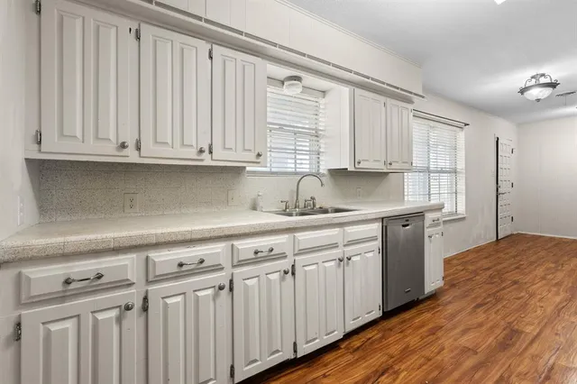 a kitchen with granite countertop white cabinets and sink