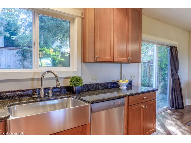 9506 Southwest Boones Ferry Road Portland, OR 97219 - Photo 12 of 32 a kitchen with granite countertop a sink a stove and wooden cabinets