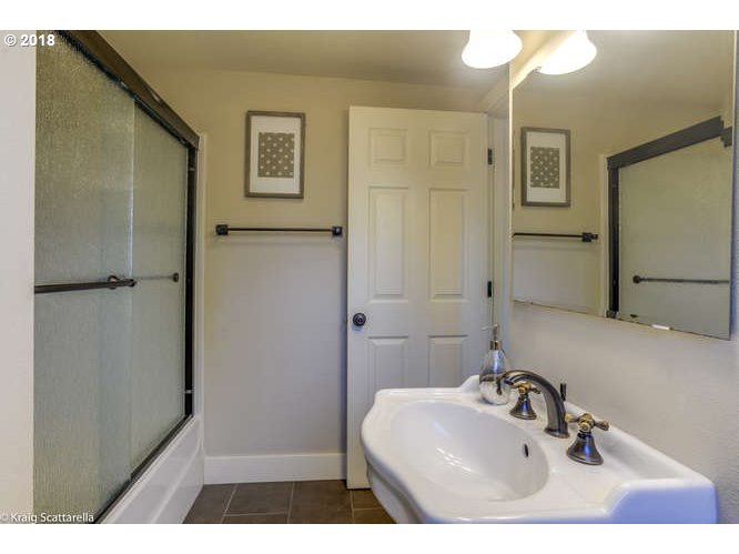 9506 Southwest Boones Ferry Road Portland, OR 97219 - Photo 19 of 32 a bathroom with a sink a mirror and shower