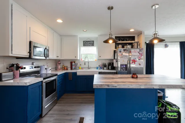 a kitchen with stainless steel appliances granite countertop a sink a stove and a wooden floors