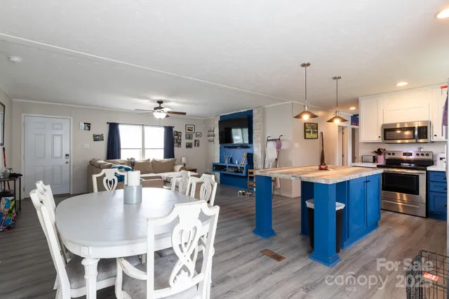 a dining area with stainless steel appliances kitchen island granite countertop a table chairs and a kitchen view