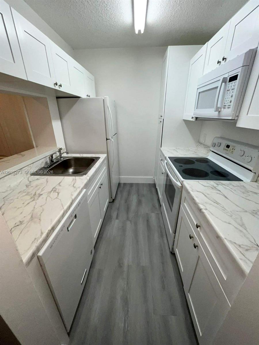 4561 West McNab Road, Unit 17 Pompano Beach, FL 33069 - Photo 4 of 11 a kitchen with granite countertop a sink and a stove top oven