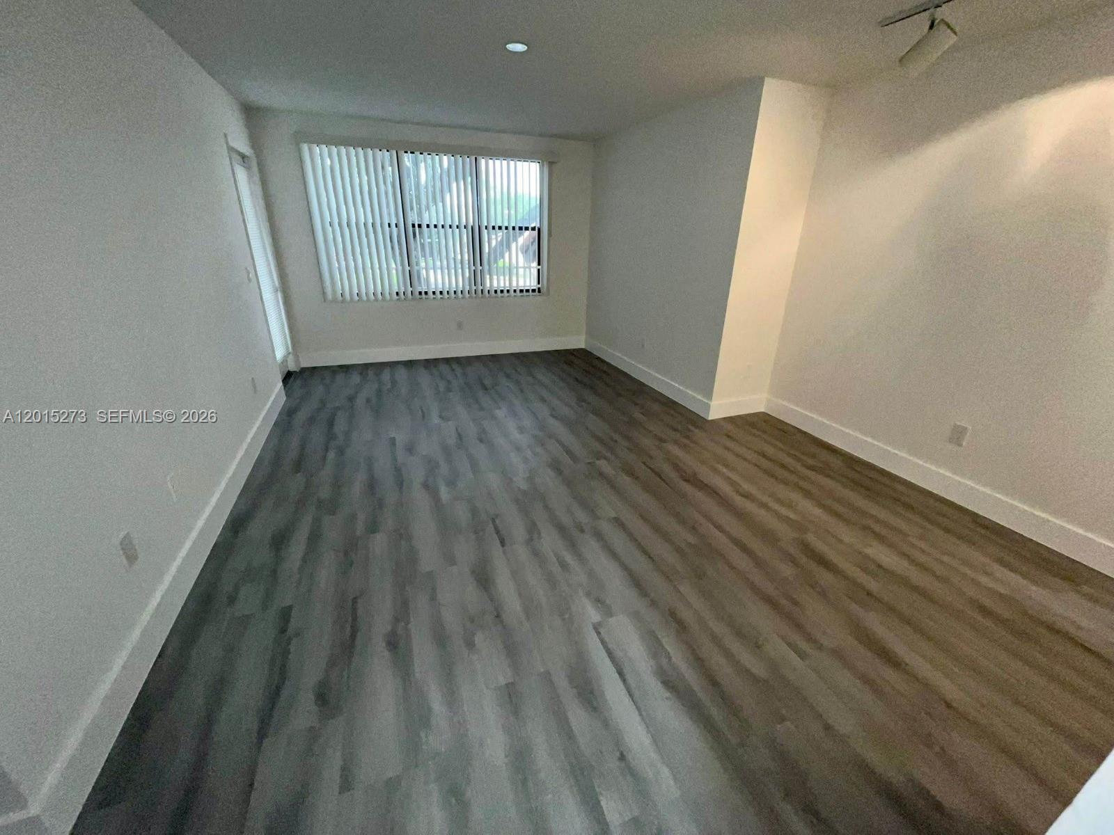 4561 West McNab Road, Unit 17 Pompano Beach, FL 33069 - Photo 5 of 11 an empty room with wooden floor and windows