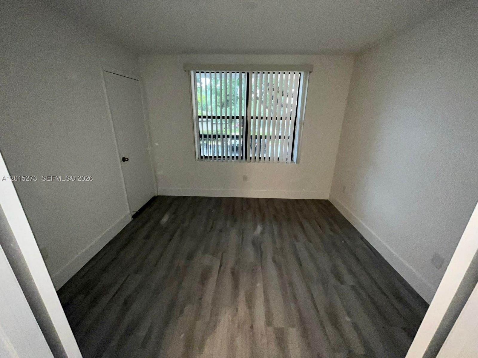 4561 West McNab Road, Unit 17 Pompano Beach, FL 33069 - Photo 7 of 11 wooden floor in an empty room with a window