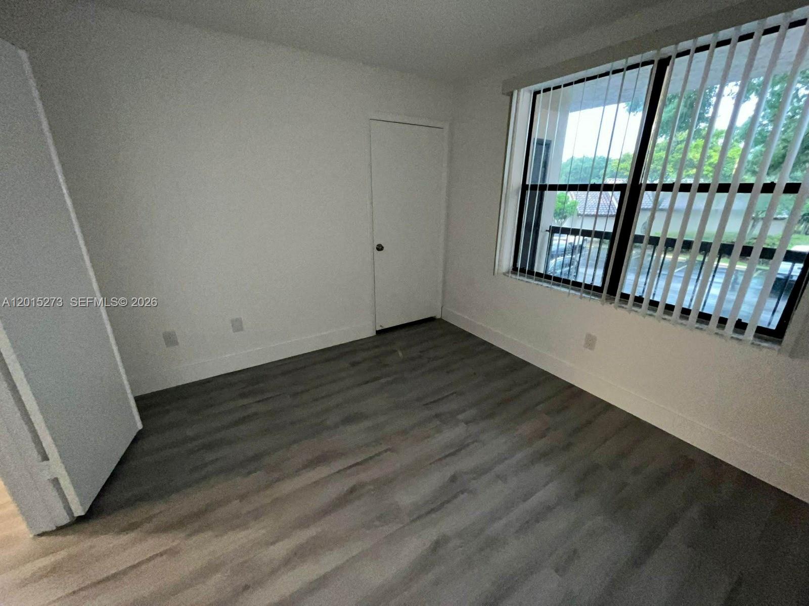 4561 West McNab Road, Unit 17 Pompano Beach, FL 33069 - Photo 8 of 11 a view of an empty room with wooden floor and a window