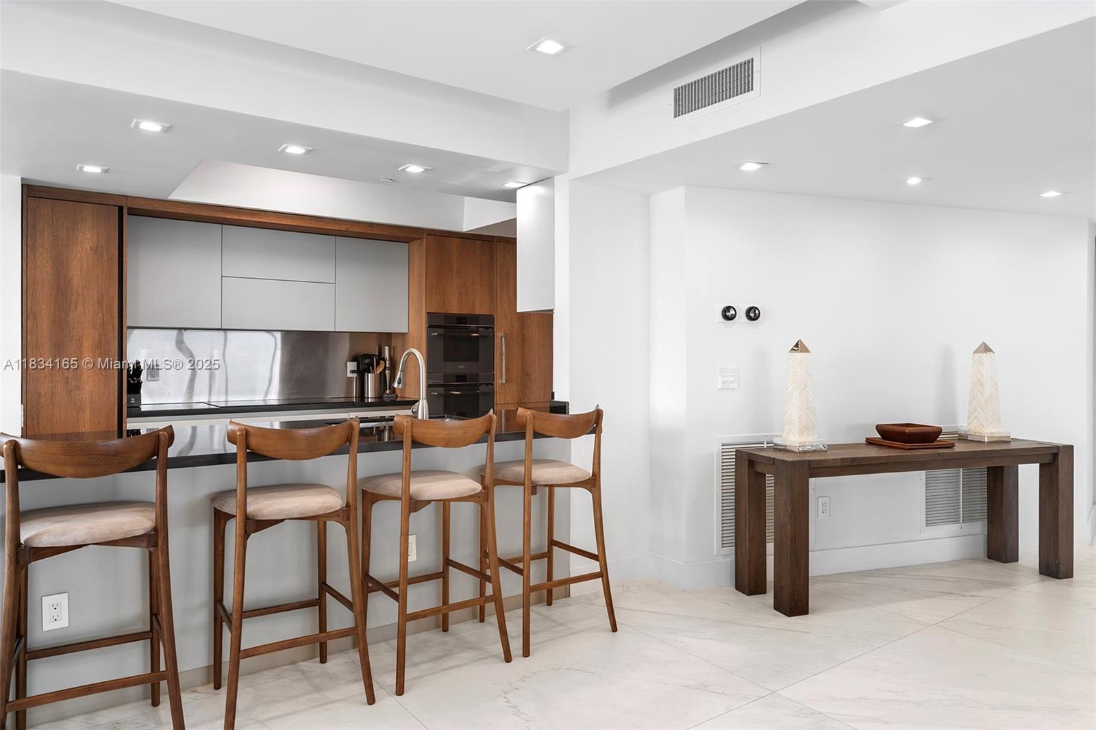 450 Alton Road, Unit 901902 Miami Beach, FL 33139 - Photo 10 of 100 a kitchen with stainless steel appliances kitchen island granite countertop a table and chairs in it