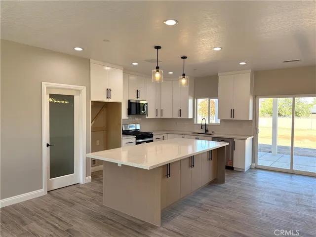 a large kitchen with kitchen island a sink stainless steel appliances and wooden floor