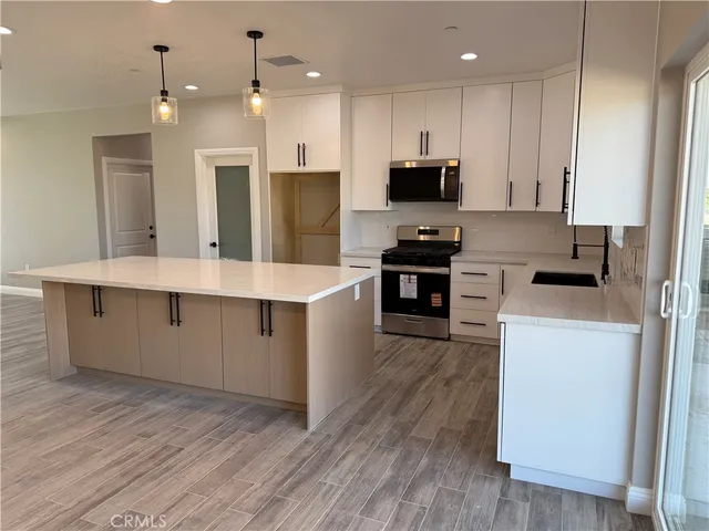 a large kitchen with stainless steel appliances kitchen island granite countertop a stove a sink a refrigerator and a microwave