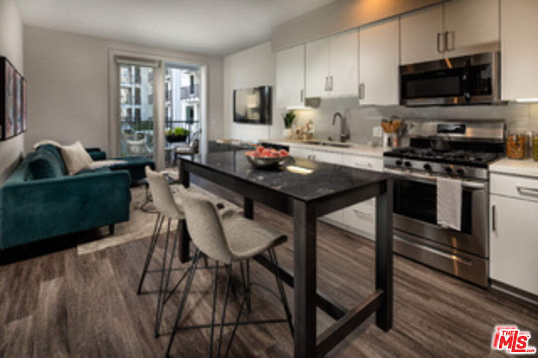 687 South Hobart Boulevard, Unit 327 Los Angeles, CA 90005 - Photo 21 of 21 a kitchen with a table chairs microwave and cabinets