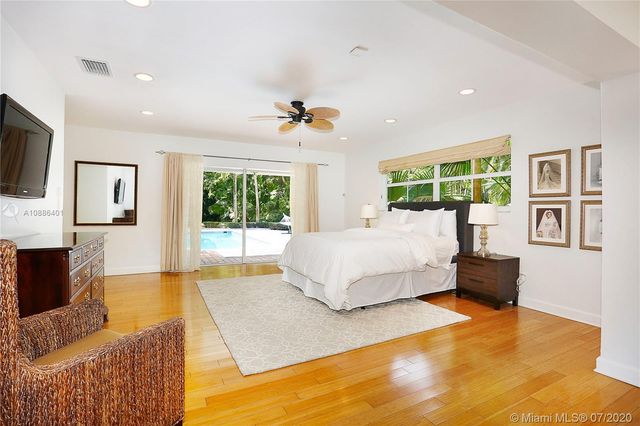 a spacious bedroom with a large bed a flat tv screen and dresser