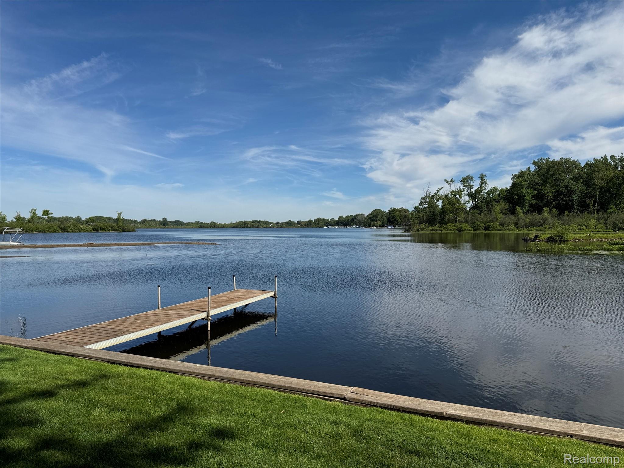 3138 Ponemah Drive Fenton, MI 48430 - Photo 17 of 19 Waterfront property featuring a private dock extending into the lake, a lush green lawn, and a natural tree line along the shore
