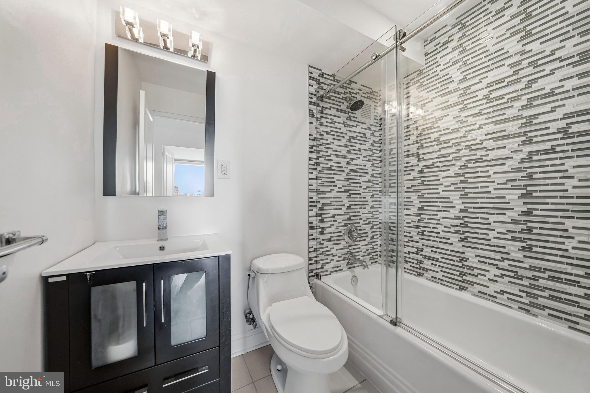 210 Locust Street, Unit 7BW Philadelphia, PA 19106 - Photo 25 of 34 a bathroom with a granite countertop toilet a sink a mirror and shower