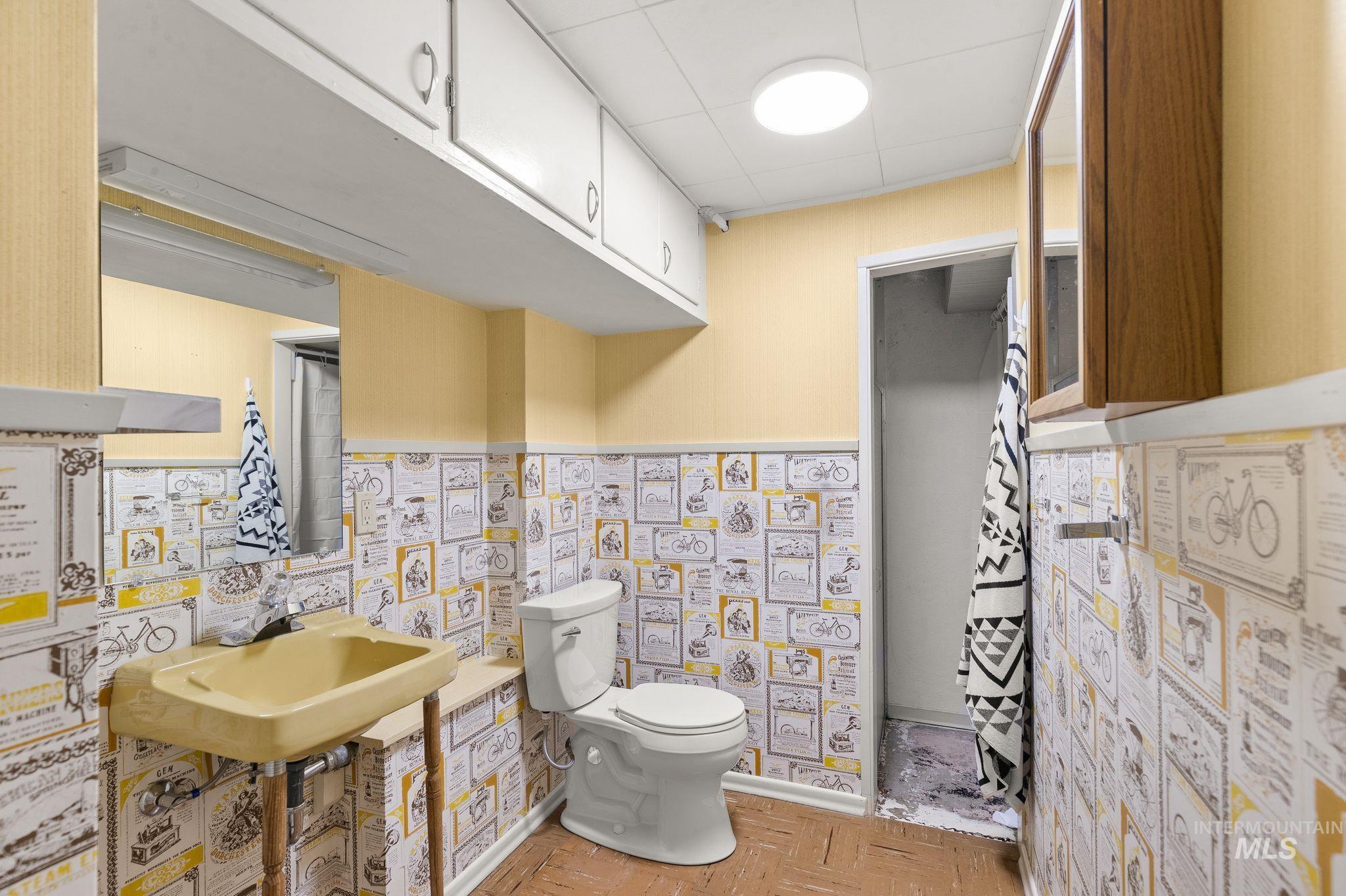 1315 8th Street Clarkston, WA 99403 - Photo 23 of 37 Bathroom with a wall-mounted sink, toilet, and patterned wainscoting