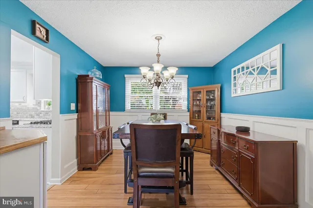 a dining room with furniture a chandelier and wooden floor