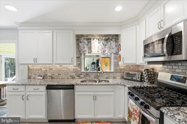 a kitchen with stainless steel appliances granite countertop a sink stove cabinets and a window
