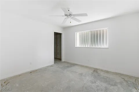 an empty room with a chandelier fan and windows
