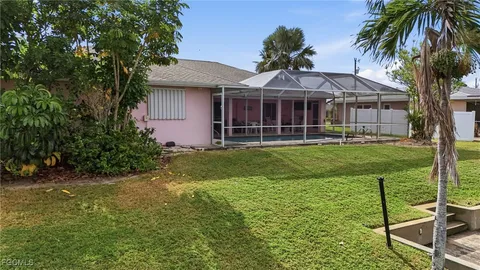 a view of a house with a yard plants and large tree