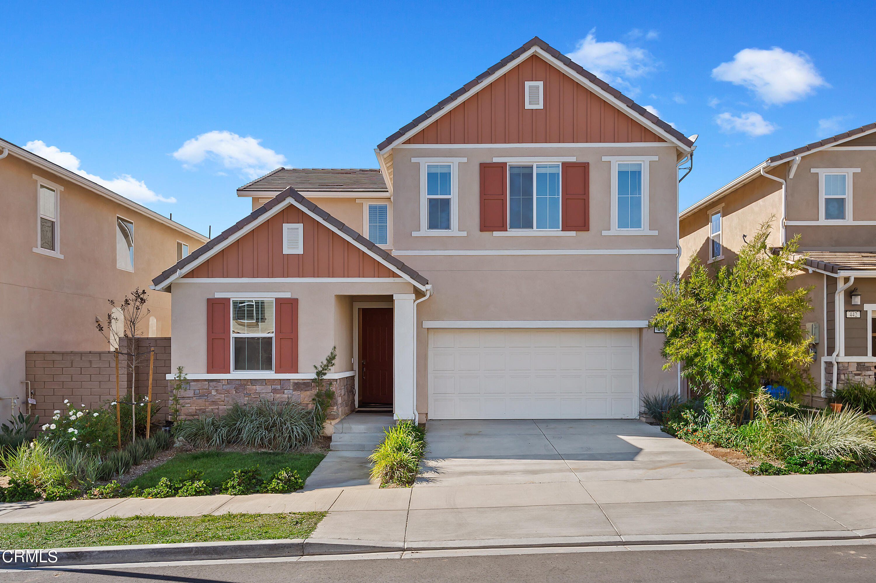 a front view of a house with a yard and potted plants