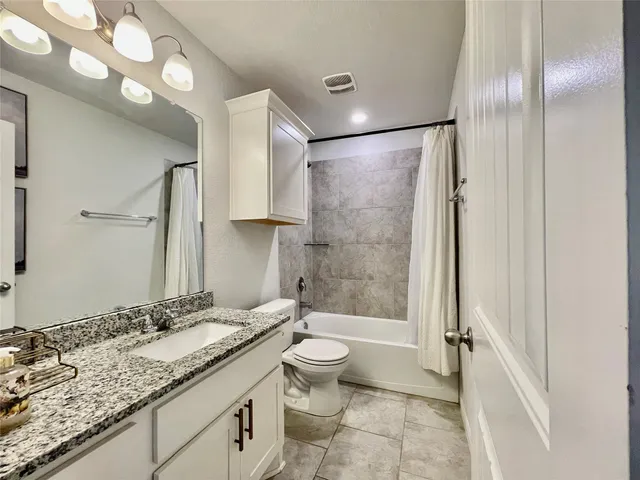 a bathroom with a granite countertop sink toilet and shower