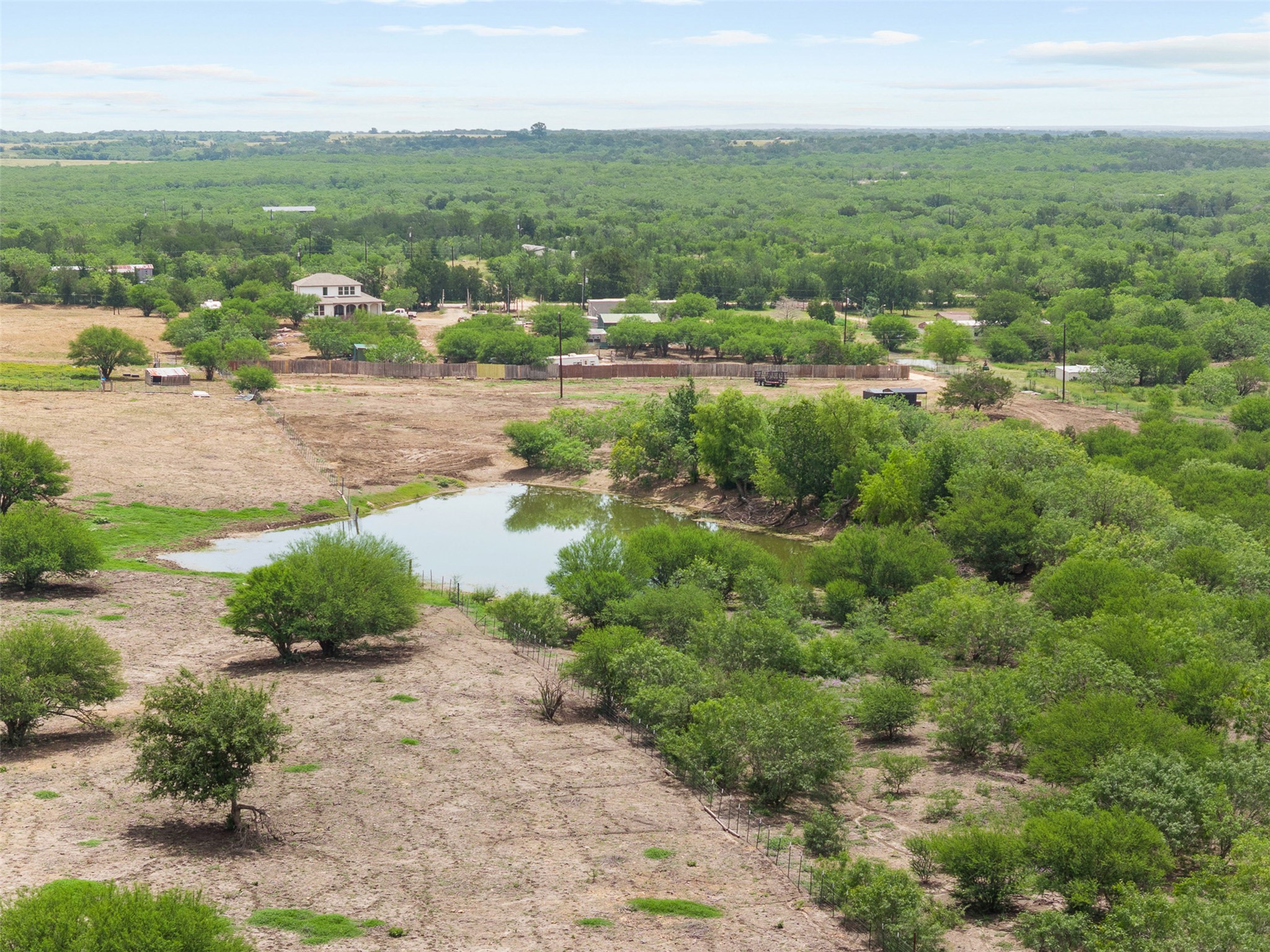 3315 Dry Creek Road Lockhart, TX 78644 - Photo 11 of 26 A tranquil pond nestles amidst a vast, verdant landscape, showcasing the property's natural beauty.