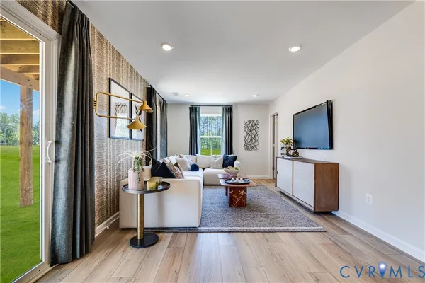 a living room with furniture a flat screen tv and a refrigerator