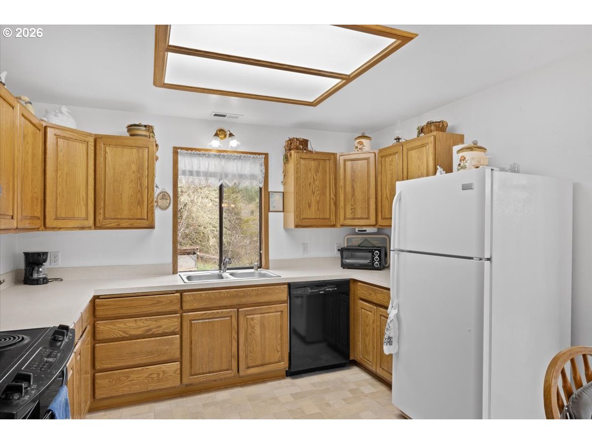 2277 Cougar Creek Road Oakland, OR 97462 - Photo 11 of 34 a kitchen with a refrigerator a sink and cabinets