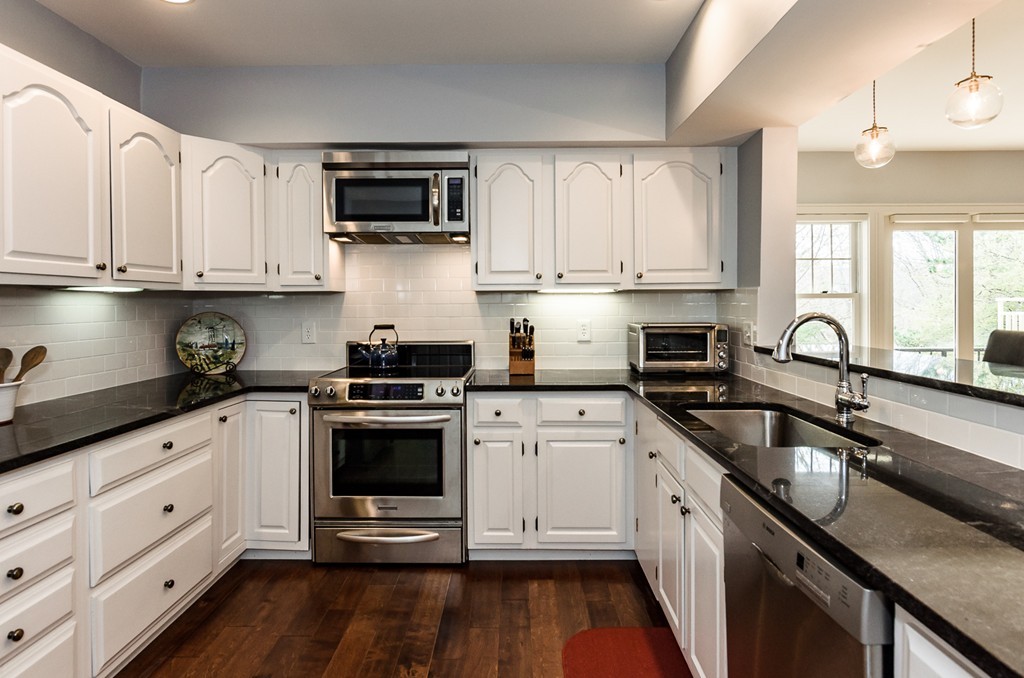 a kitchen with stainless steel appliances granite countertop a sink and dishwasher a stove top oven with wooden floor
