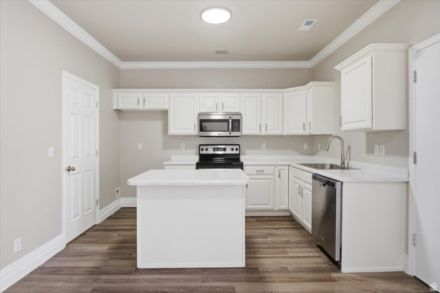 4496 West 11800 South South Jordan, UT 84009 - Photo 8 of 33 Kitchen with white cabinets, stainless steel appliances, light countertops, a kitchen island, and dark wood-type flooring