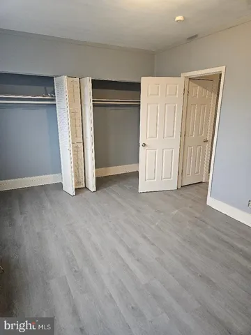 an empty room with wooden floor and closet area