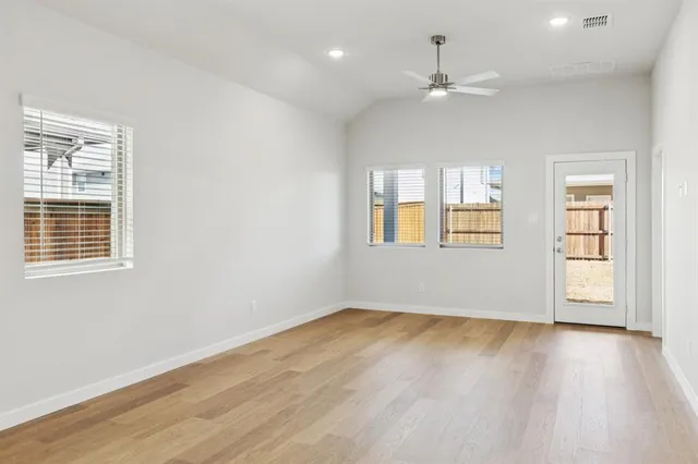 an empty room with windows and ceiling fan