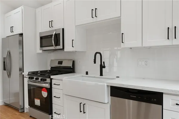 a kitchen with stainless steel appliances a sink stove and white cabinets