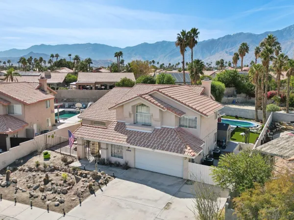 a front view of a house with a yard and mountain view in back