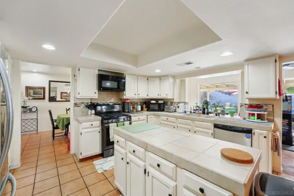 a kitchen with stainless steel appliances granite countertop a stove top oven a sink a dining table and chairs with white cabinets