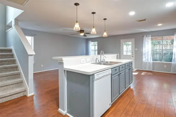 a kitchen with a sink a chandelier stainless steel appliances and wooden floor