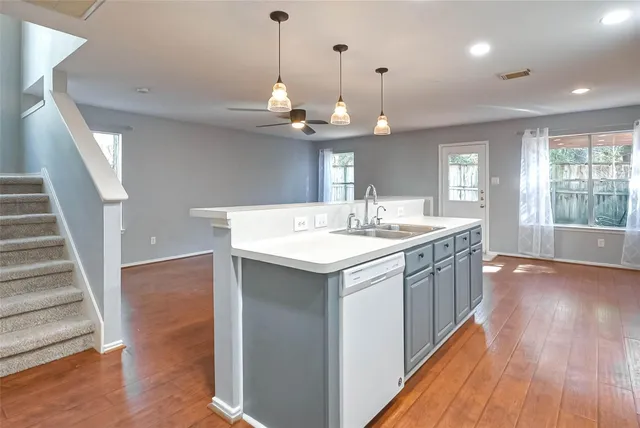 a kitchen with a sink a chandelier stainless steel appliances and wooden floor