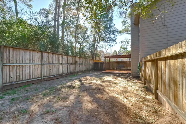 a view of backyard with wooden fence and large trees